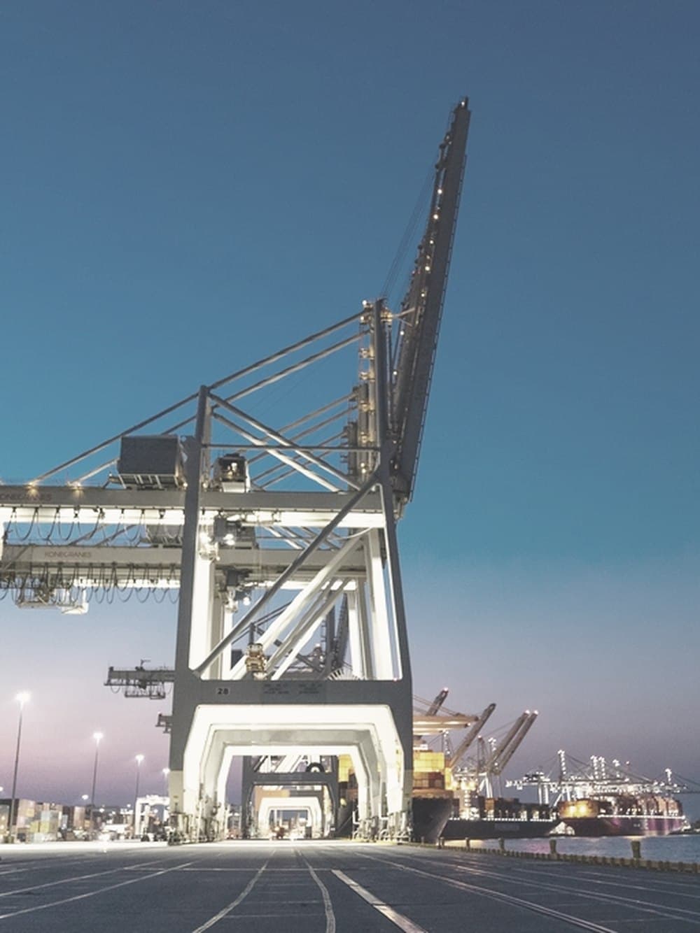 Grúas de muelle sobre una explanada portuaria al anochecer.